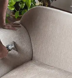 Professional upholstery cleaner deep-cleaning a fabric sofa with a handheld extraction tool and hose Oakland, CA.